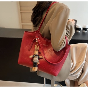 Detail of red tote bag featuring a cute rabbit charm and textured synthetic leather