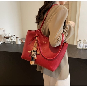 Detail view of large red retro tote bag with golden lettering and cute plush rabbit charm