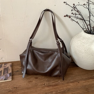 Detail of vintage coffee brown tote bag with adjustable buckled straps on wooden base