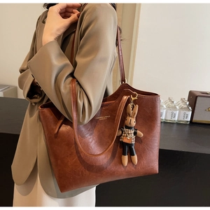 Detailed shot of a vintage brown tote bag with fashion lettering and a cute rabbit charm