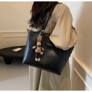 Close-up of black textured leather tote bag featuring a cute rabbit charm and logo