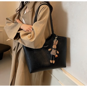 Detailed view of black PU leather tote bag featuring a bunny charm and model lifestyle styling