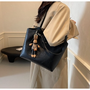 Detail of black tote bag with cute rabbit pendant and fashion text on textured leather