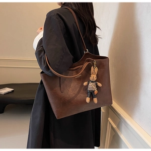 Detail view of large brown vintage tote bag featuring a cute rabbit charm and gold lettering