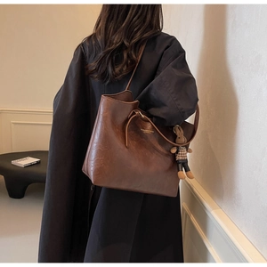 Detail of dark brown leather tote bag with drawstring accents and plush rabbit pendant