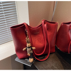 Detail of red PU leather tote bag featuring golden lettering and a cute bunny pendant