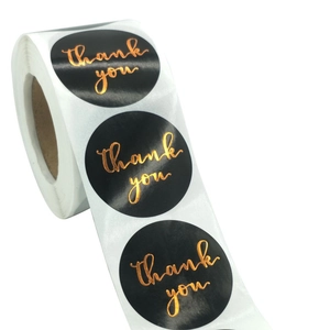 Detailed view of black round thank you stickers with gold foil lettering in a roll