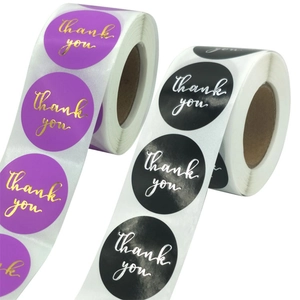 Close-up of gold and silver foil thank you labels on purple and black sticker rolls