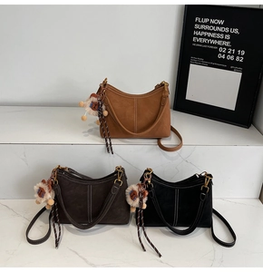 Détail de sacs hobo pour femmes en daim marron, café et noir avec breloques lion mignonnes