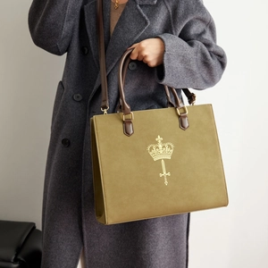 Detail of olive green suede tote bag with golden crown logo and vintage leather handles