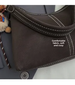 Gros plan sur le cuir marron grainé du sac avec coutures blanches contrastées