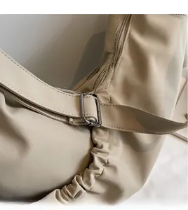 Close-up of adjustable long shoulder strap and pleat details on khaki crescent bag