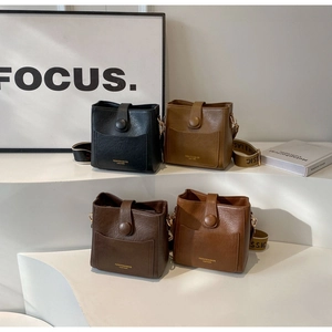 Detail of vintage square bucket bags in four colors with wide lettered shoulder straps