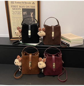 Détails de quatre sacs seaux mats en noir, marron et bordeaux avec des breloques d'ours