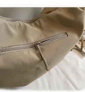 Close-up of smooth FNER branded metal zipper on khaki nylon dumpling shoulder bag
