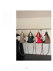 Detail of four faux leather bucket bags in beige, black, red, and brown with bunny charms