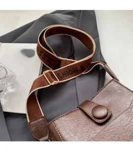 Close-up of brown vintage bucket bag with an embroidered wide strap and golden hardware