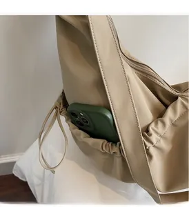 Close-up of side drawstring pocket on beige nylon shoulder bag showing phone storage