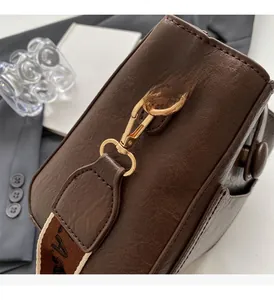 Close-up of golden metal buckle and brown pebble leather texture on bucket bag