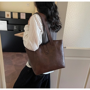 Close-up of a vintage dark brown tote bag with leather texture and long shoulder straps