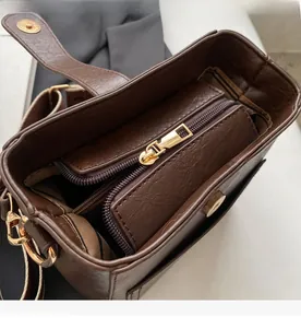 Detail view of the smooth golden zipper and magnetic snap closure on the brown bucket bag