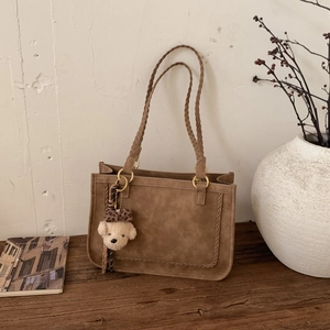 Detail of vintage brown suede tote with braided handle and cute teddy bear charm accessory