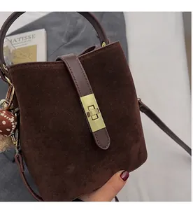 Détail du sac seau en daim marron avec fermoir rotatif doré et bandoulière élégante
