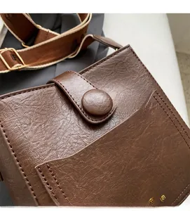 Detail of vintage brown crossbody bag with retro buckle and textured faux leather