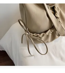 Detailed close-up of pleated fabric and elegant bow knot on the beige crossbody bag