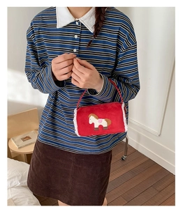 Detail of red plush handbag with cute pony embroidery and white faux fur trim on model