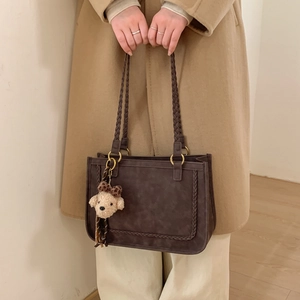 Close-up of retro brown tote bag with woven handles and a cute puppy plush charm