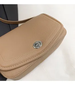 Detalle de bolso en cuero granulado caqui con cierre giratorio de metal plateado