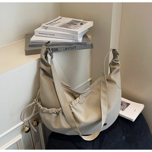 Detail of a beige dumpling-style crossbody bag with stylish pleated and drawstring elements