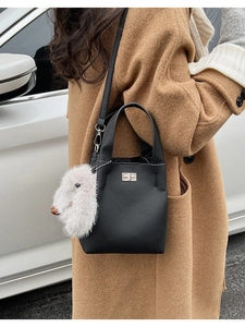 Detail of black lychee grain leather bucket bag with silver twist lock and plush rabbit charm