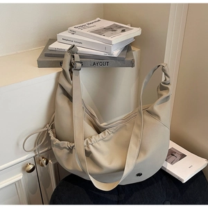 Detailed close-up of cream beige dumpling bag with soft pleats and smooth zipper closure