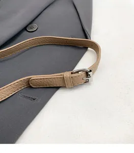 Detalle de correa ajustable en cuero caqui con textura litchi y hebilla metálica plata