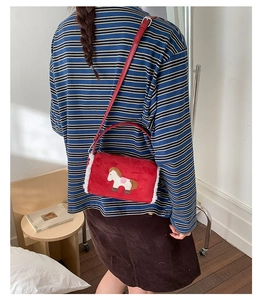 Detail of red plush bag featuring cartoon horse embroidery and white fleece trim