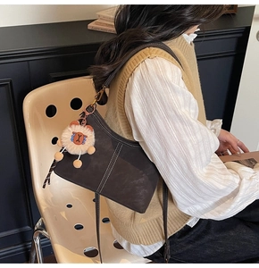 Détail du sac seau marron foncé en daim avec surpiqûres contrastées et breloque peluche