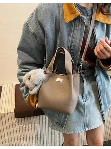 Detail of taupe pebbled leather bucket bag with metal twist lock and plush rabbit charm