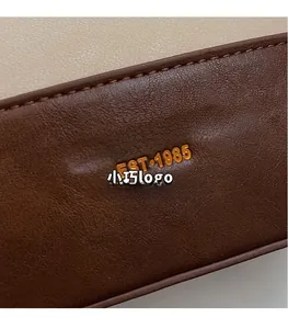 Détail macro du logo doré sur le sac seau en cuir vintage marron et beige élégant