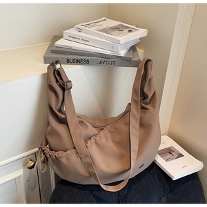 Macro view of khaki nylon crossbody bag featuring drawstring side pockets and wide strap