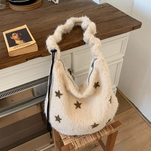 Detail of plush hobo bag showing star patterns, pleated handles and metal zipper texture