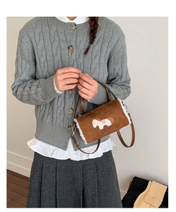 Detail of plush brown bucket bag with white faux fur trim and horse embroidery