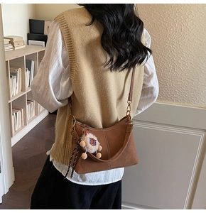 Sac bandoulière marron en forme de demi-lune avec coutures et breloque ours mignonne