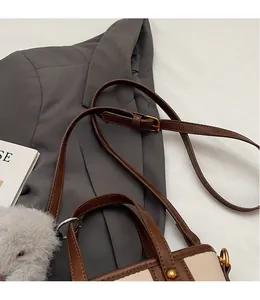 Gros plan sur la bandoulière en cuir marron et les boucles dorées du sac à main