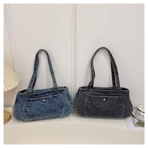 Close-up of denim shoulder bags in washed blue and charcoal black with metal rivets