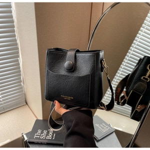 Détail du sac seau noir avec bandoulière tissée large et poche frontale rétro
