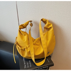 Detail of ginger yellow PU leather shoulder bag featuring drawstring and smooth metal zipper