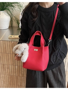 Detail of red lychee pattern bucket bag with silver twist lock and grey rabbit charm