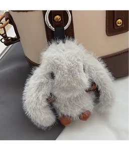 Gros plan d'un pendentif lapin en peluche gris avec anneau argenté sur un sac à main